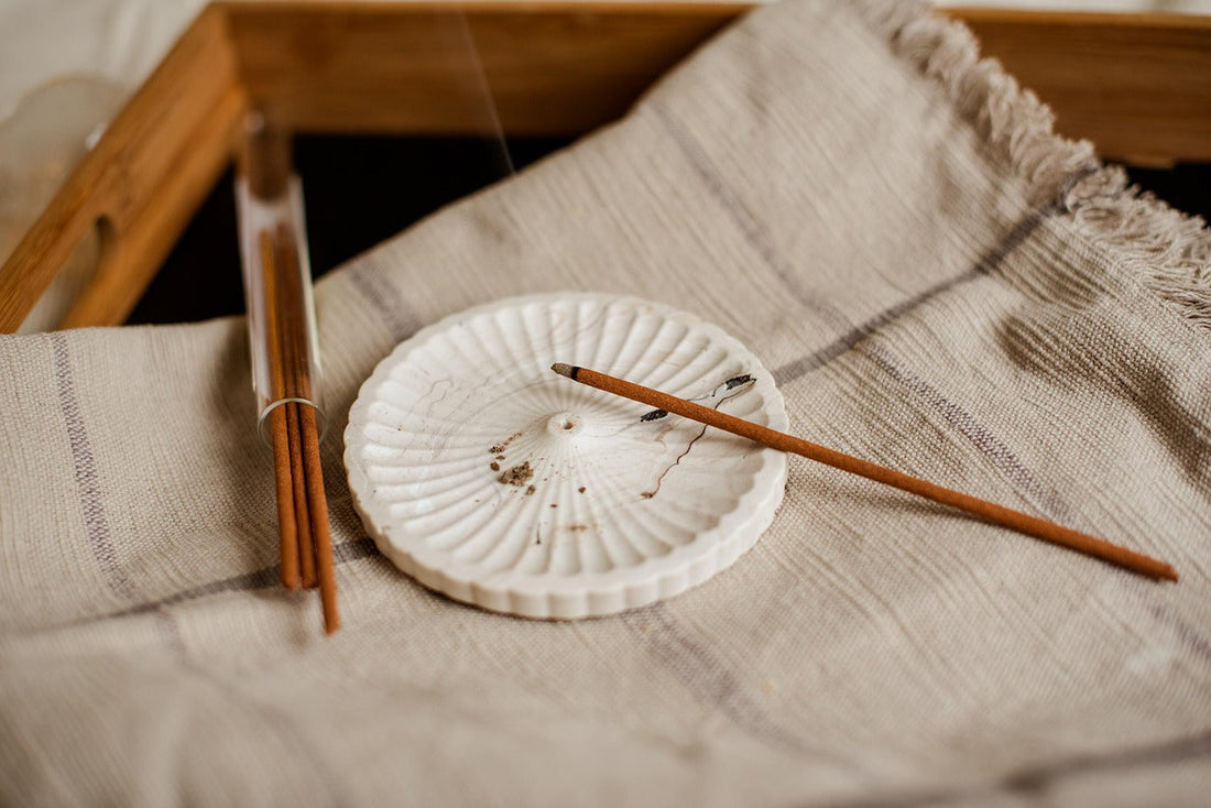 Ceramic incense holder with Chomolung Snow Tibetan incense sticks on a textured fabric surface
