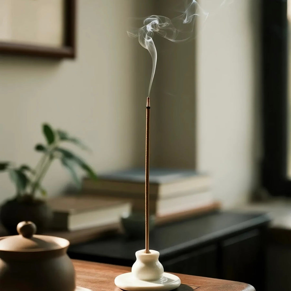 Burning Tibetan incense stick releasing gentle smoke during a calm home ritual.