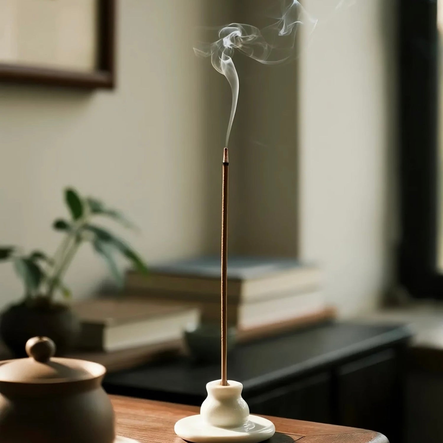 Burning Tibetan incense stick releasing gentle smoke during a calm home ritual.