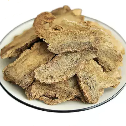 Sliced pieces of Dolomiaea souliei, a medicinal herb native to China, arranged on a white plate with a textured surface.