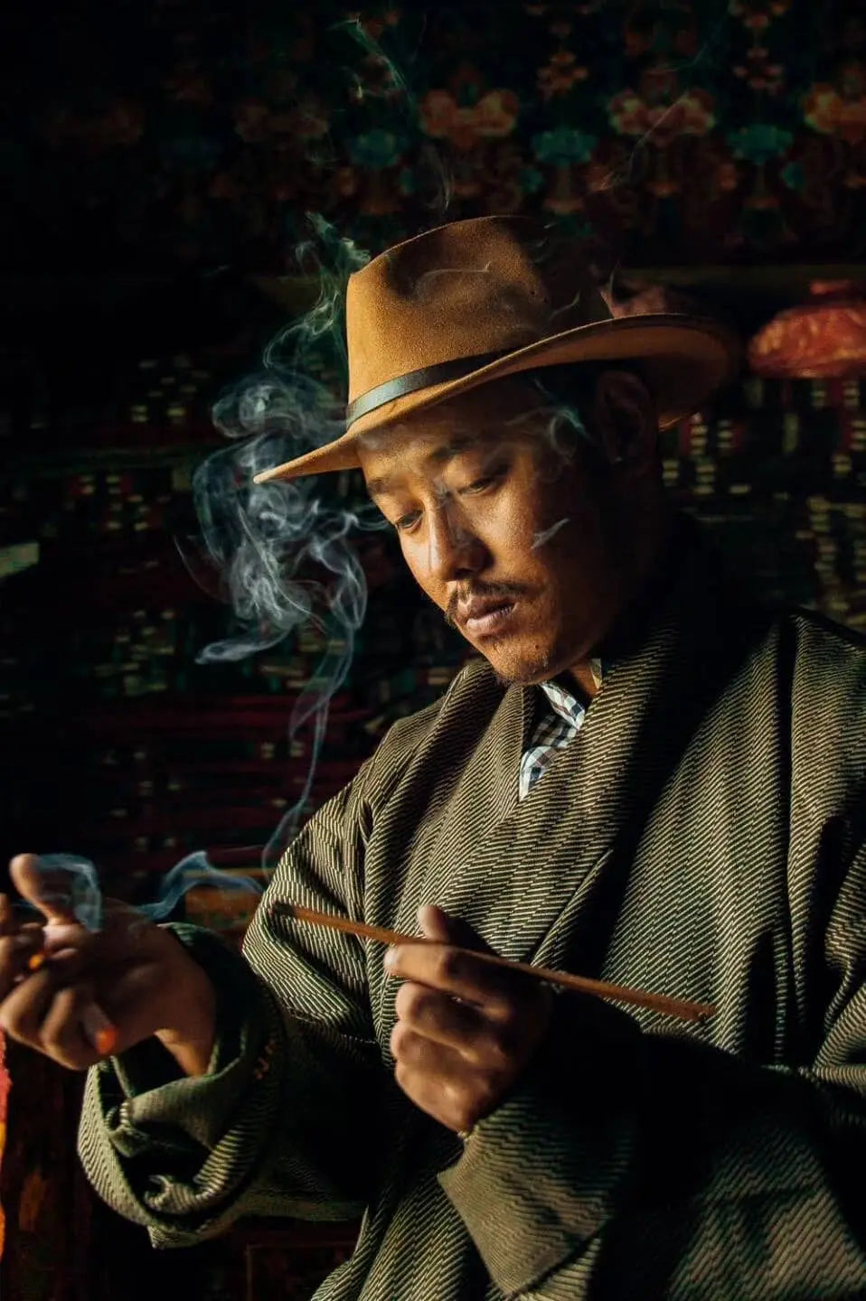 Man performing a traditional Tibetan incense ritual with handcrafted incense sticks
