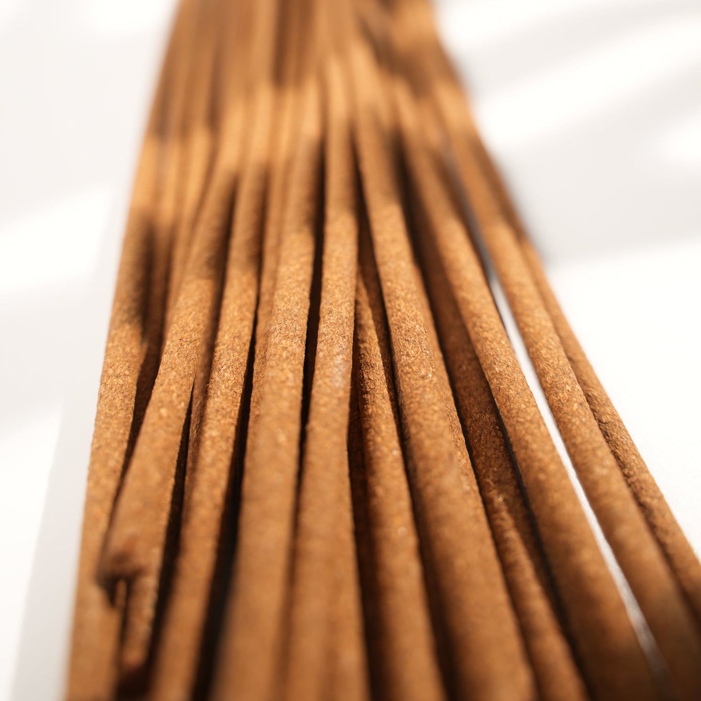 Close-up view of Chomolung Snow Tibetan incense sticks, highlighting the fine texture and warm brown tone under natural light with soft shadows.