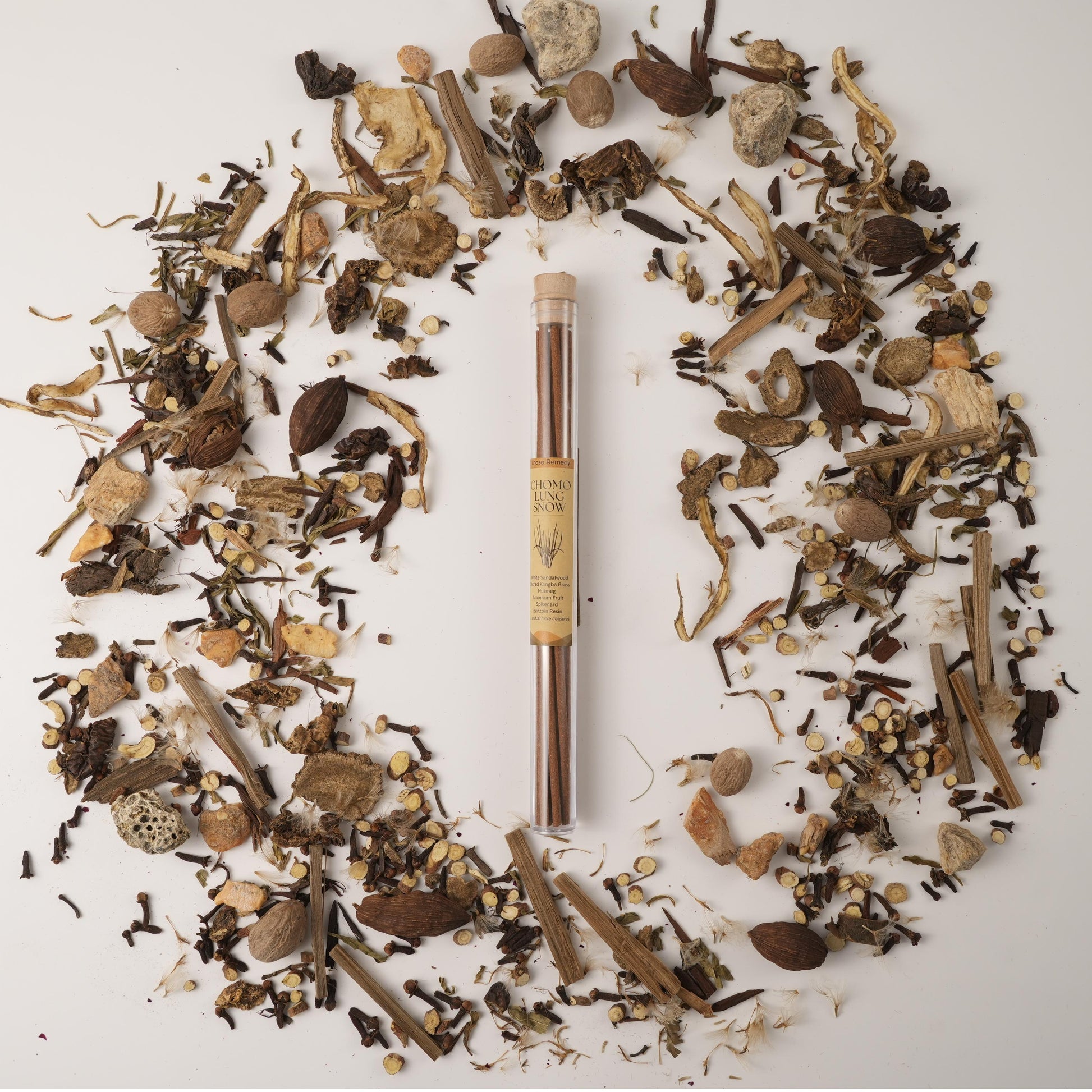 Chomolung Snow Tibetan incense sticks in a glass tube, surrounded by traditional Chinese medicinal herbs on a white background.