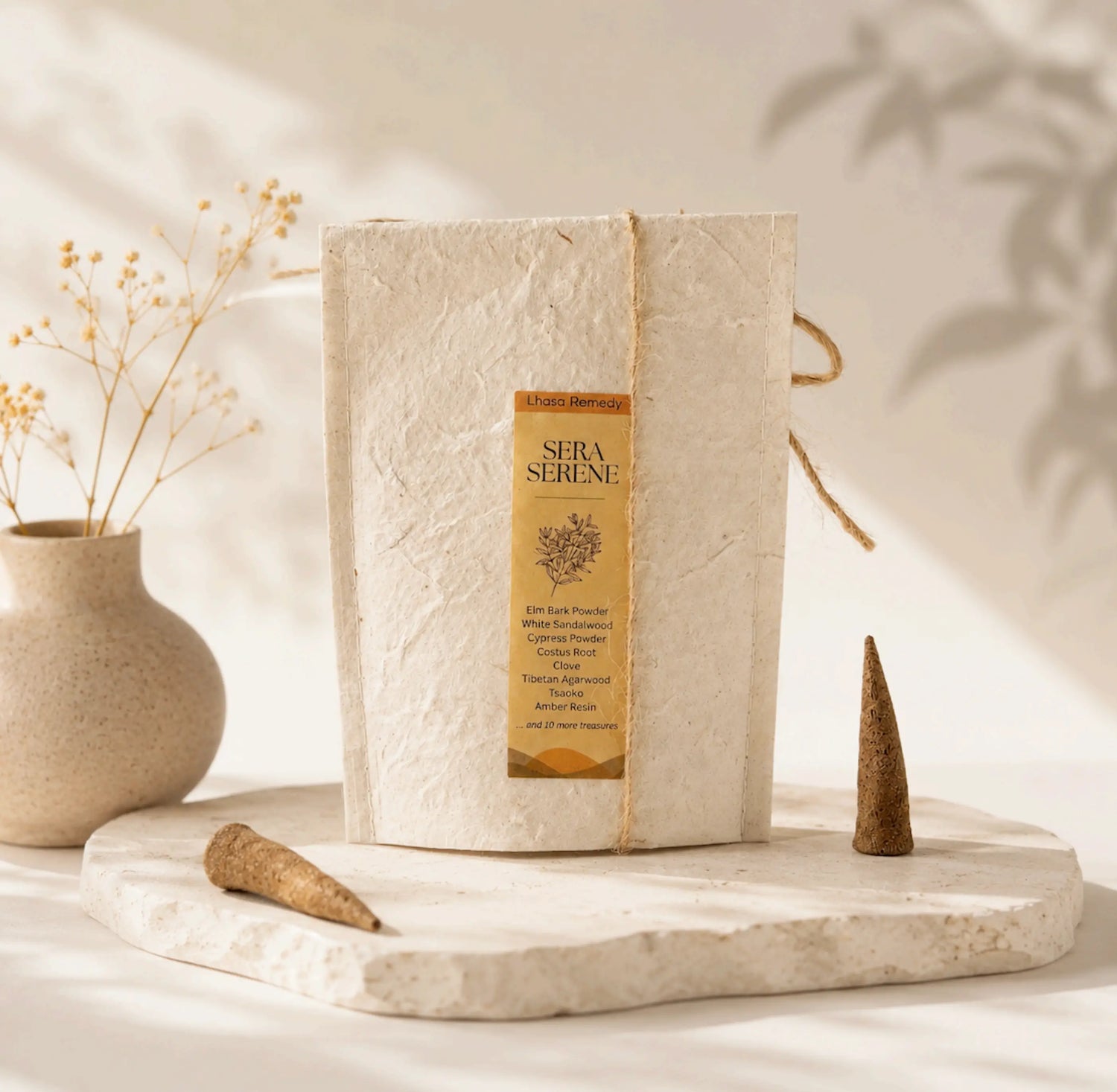 Lhasa Remedy Sera Serene Tibetan incense handmade paper packet on stone slab with two cones and dried flowers