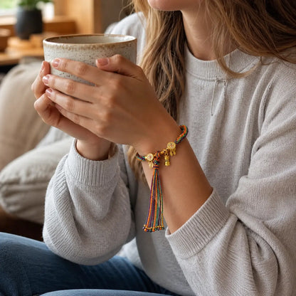 Woman wearing Lhasa Remedy Tibetan prayer bracelet gold charms colorful thread holding coffee cup