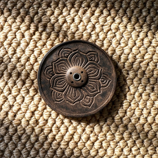 Intricately carved lotus mandala incense holder in natural wood, photographed from above with soft sunlight and shadow