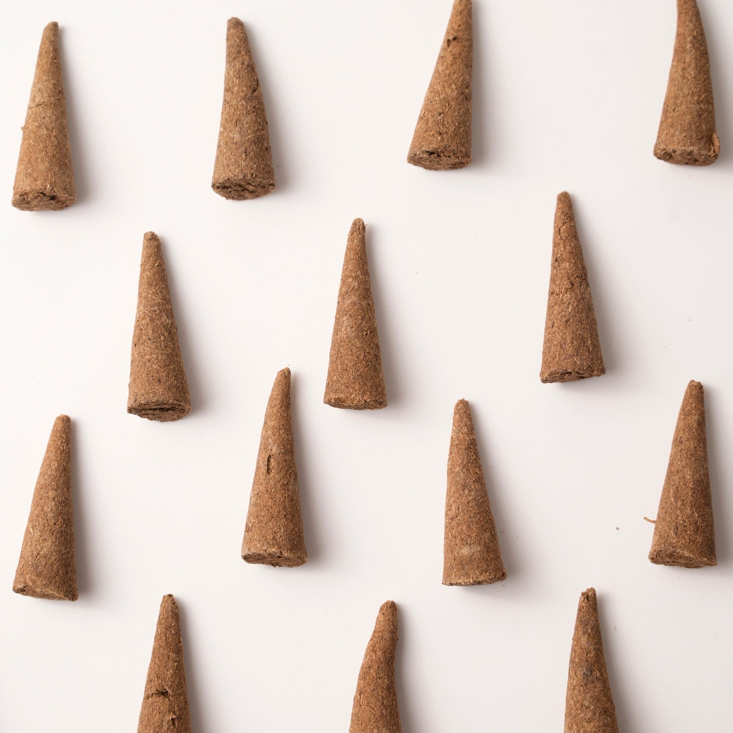 Top-down view of multiple Lucky Zaki Tibetan incense cones arranged in a neat pattern on a white background. Each cone is handcrafted and made with traditional Tibetan herbs for joy, energy, and abundance.