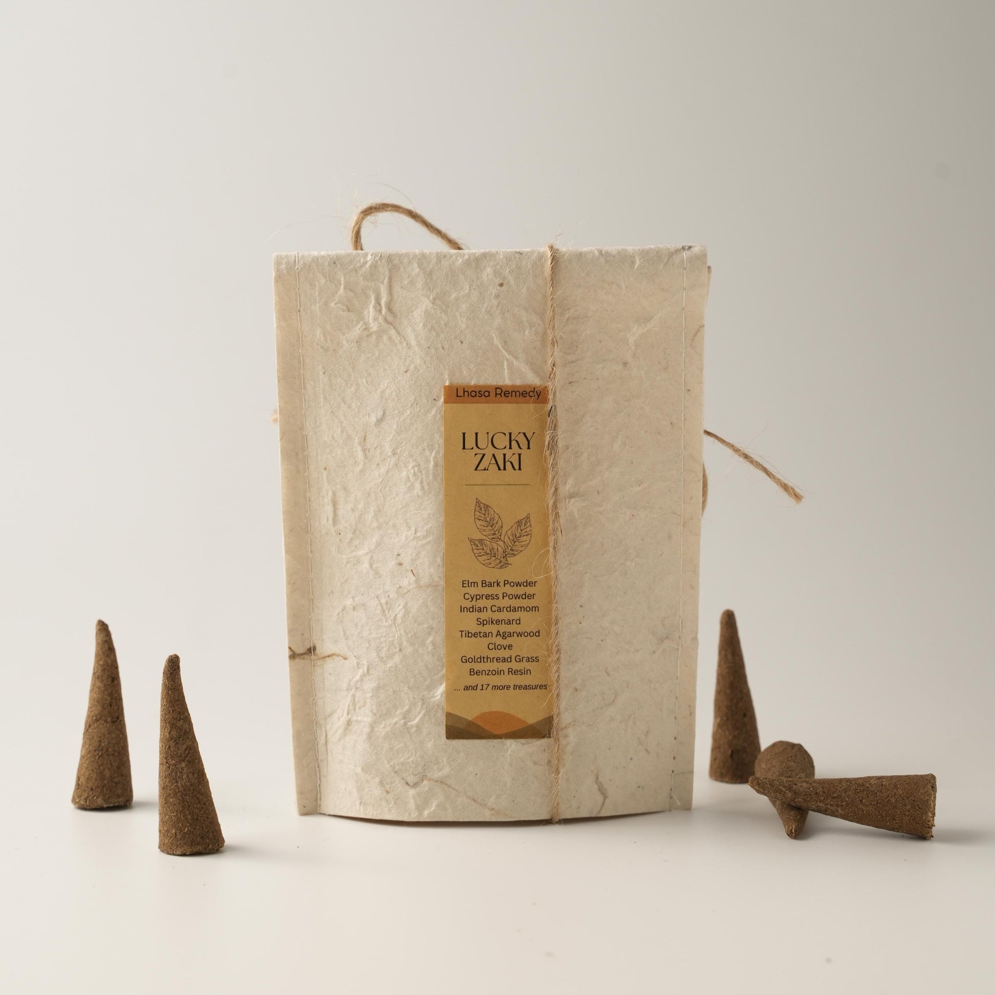 Lucky Zaki incense cones arranged beside a handmade textured paper package bag with a product label, placed on a minimal off-white background.