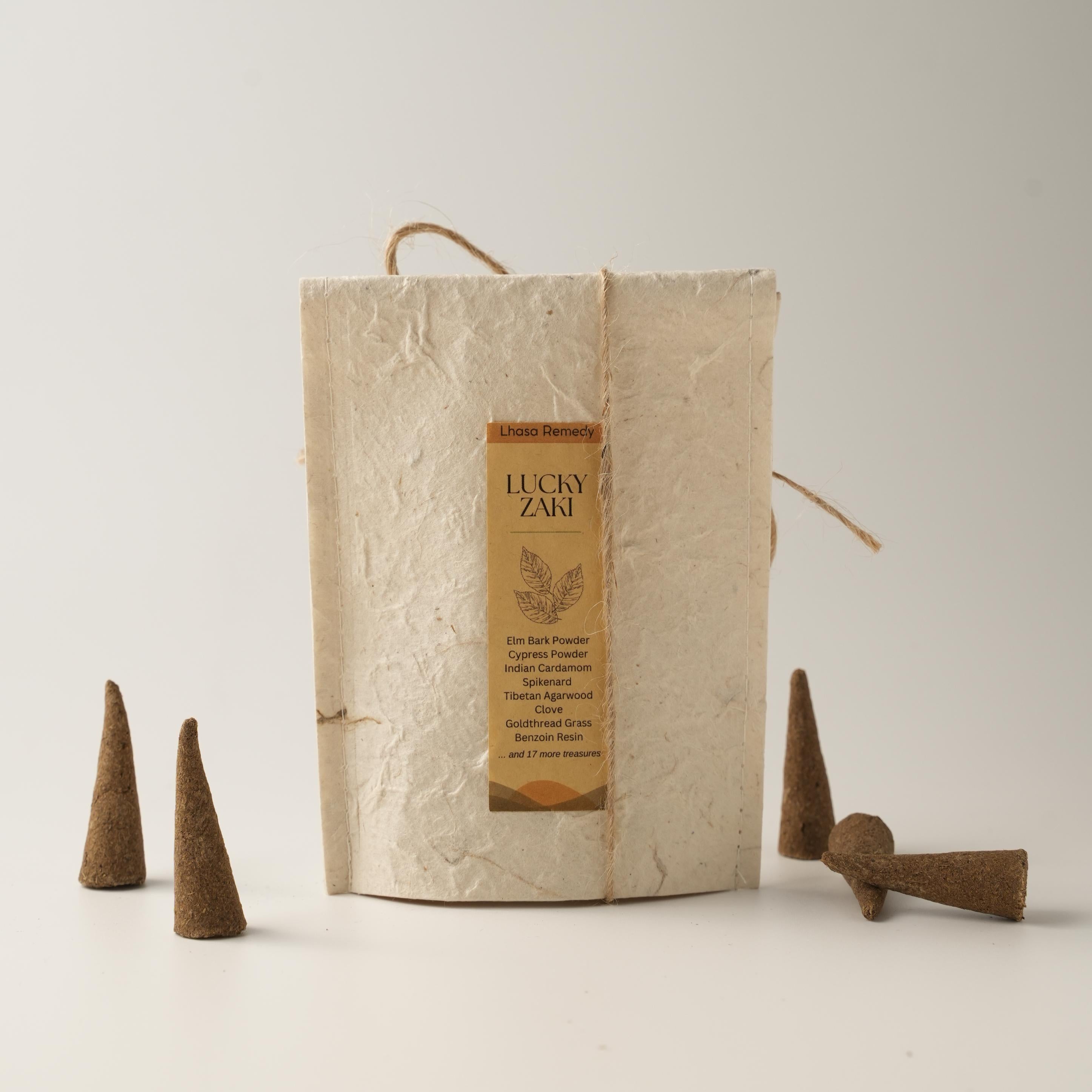 Lucky Zaki incense cones arranged beside a handmade textured paper package bag with a product label, placed on a minimal off-white background.