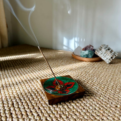 Nimu Village Tibetan incense stick burning on Lhasa Remedy’s Lotus Blossom holder, with gentle smoke curling up beside crystals and sage in a serene, sunlit space.