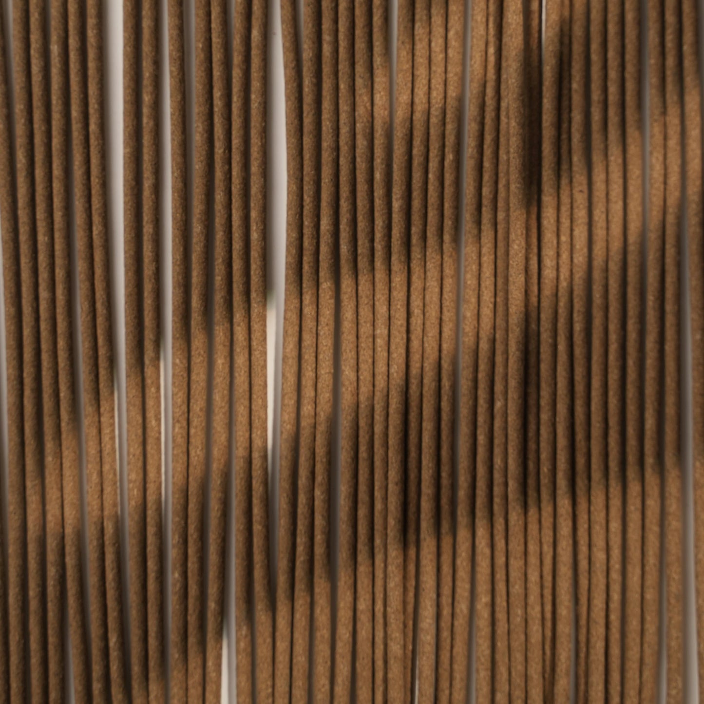 Rows of hand-rolled Nimu Village incense sticks, capturing their smooth texture and earthy tone under soft, diffused light.