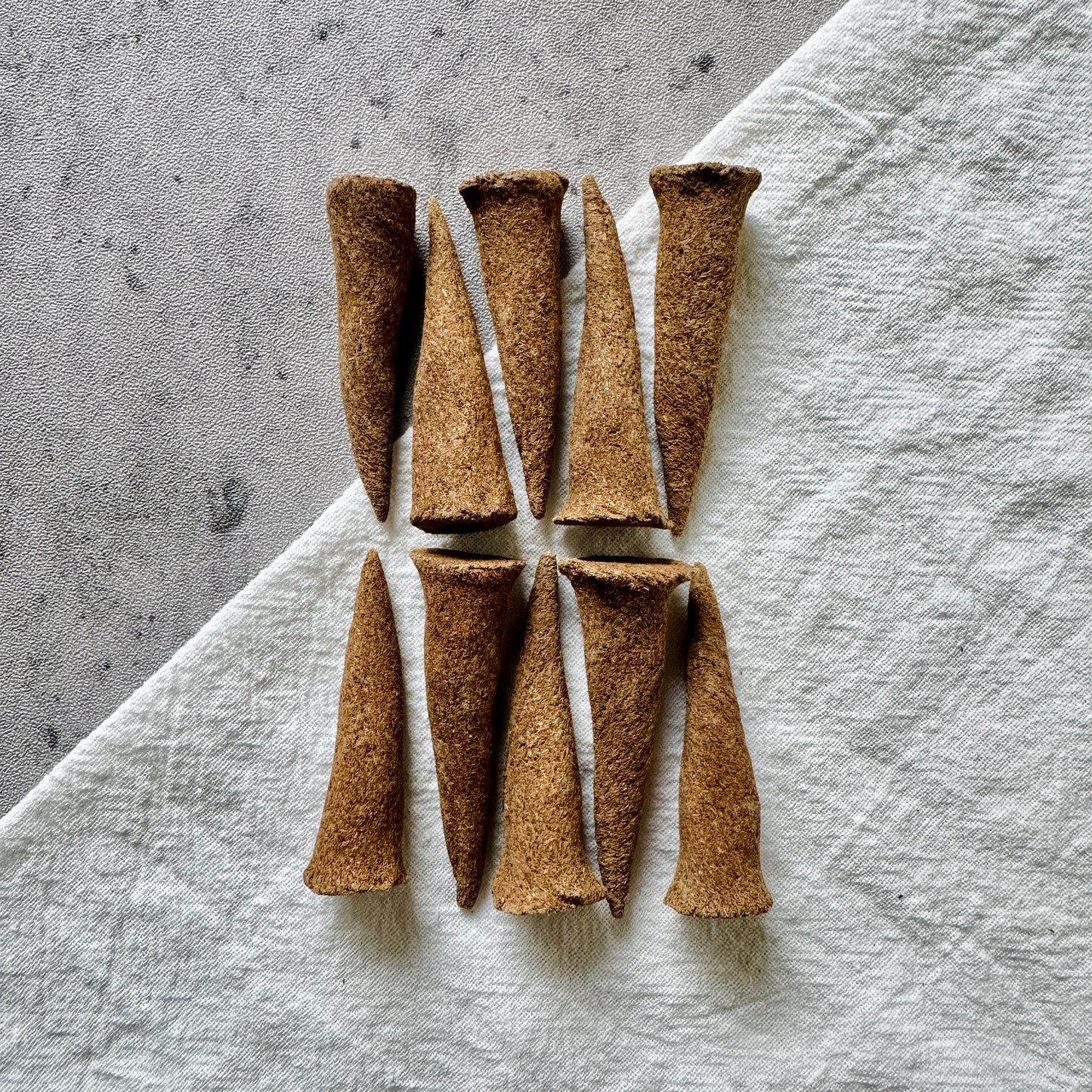 A top-down view of Sera Serene Tibetan incense cones laid on a neutral linen background, crafted for meditation, inner peace, and quiet reflection.