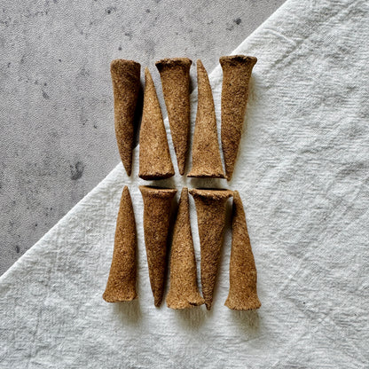 A top-down view of Sera Serene Tibetan incense cones laid on a neutral linen background, crafted for meditation, inner peace, and quiet reflection.