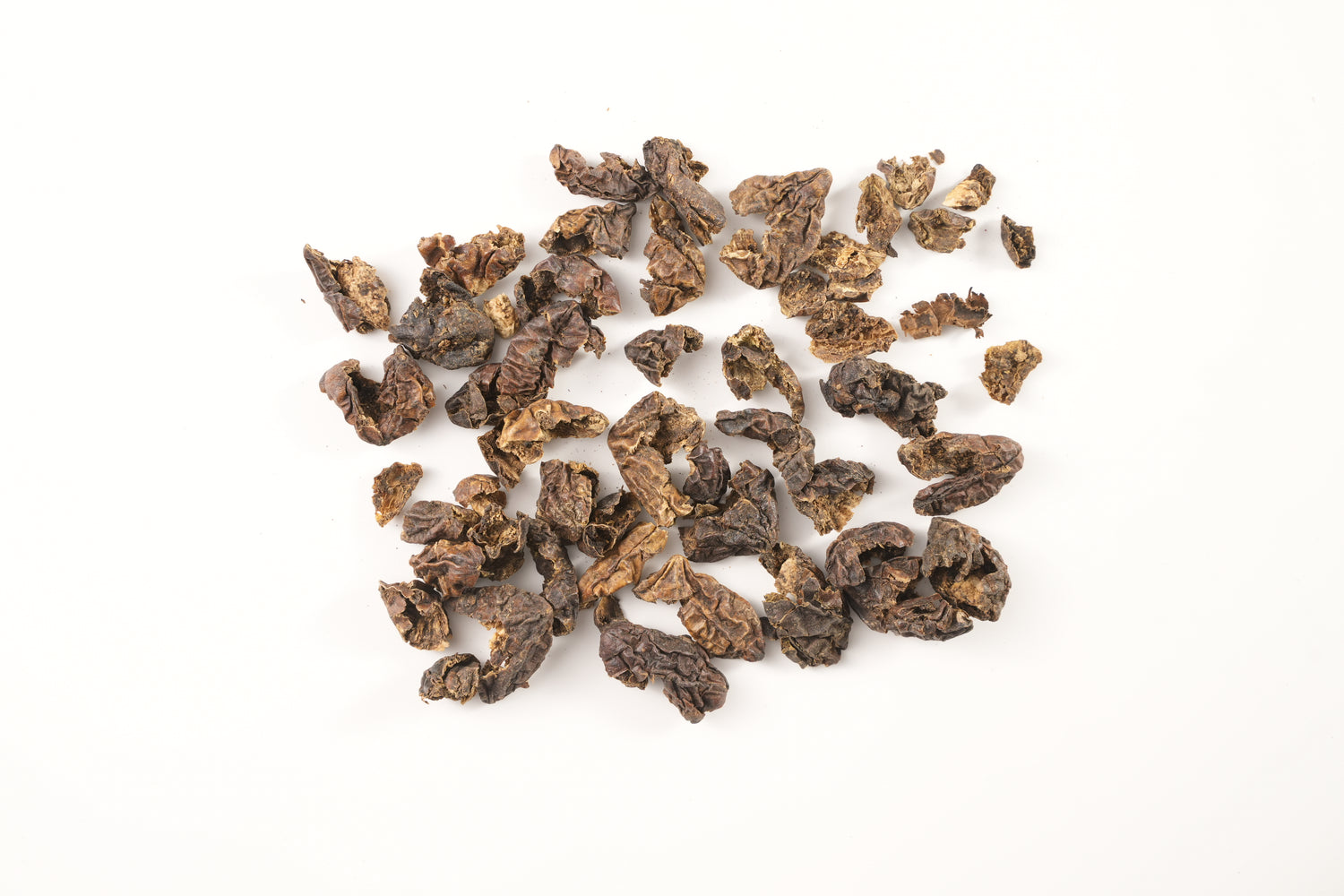 Loose dried pieces of Terminalia chebula fruit scattered on a white background. This powerful detoxifying herb supports digestion, rejuvenation, and inner balance in Tibetan and Ayurvedic traditions.