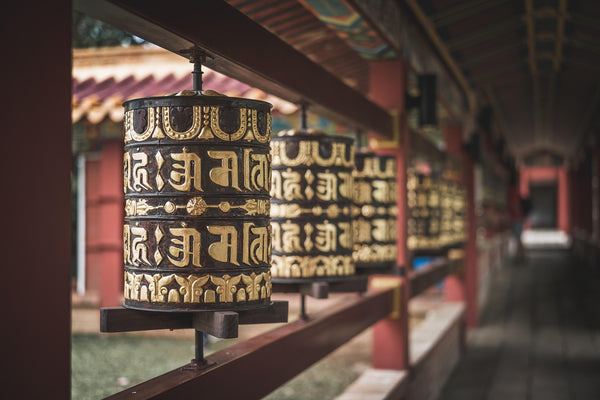 Traditional Tibetan prayer wheels lined along a monastery corridor, engraved with sacred mantras
